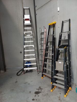 Plusieurs échelles sont alignées contre un mur dans un garage.