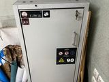 une armoire métallique sur laquelle est accrochée une pancarte, à côté d'une poubelle
