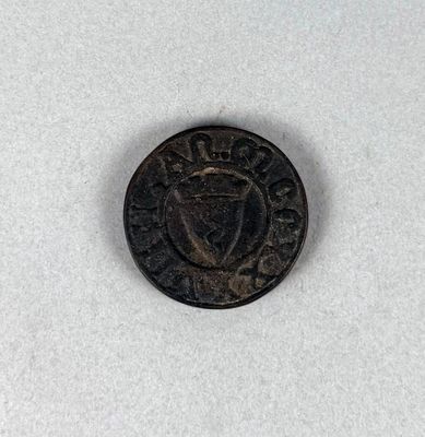 une vieille pièce de monnaie sur laquelle figure une couronne, posée sur une surface blanche