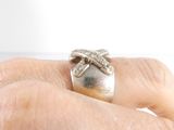 a woman ' s hand holding a silver ring with a bow on it