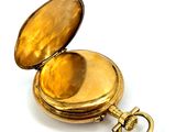 a small gold pocket watch with a key in it