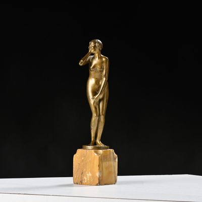 une statue antique en bronze représentant une femme, posée sur un bloc de marbre