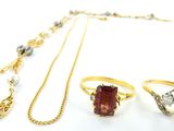 trois bagues, un collier et une bague ornée de perles sur un fond blanc