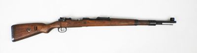 un vieux fusil avec un canon en bois sur une surface blanche