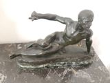 statue représentant un garçon sur une planche de surf, posée sur un socle en marbre