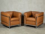 two brown leather chairs sitting next to each other on a cement floor