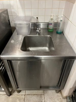 un évier dans un coin de la cuisine, avec un plan de travail en acier inoxydable