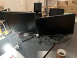 three computer monitors sitting on a desk in a room