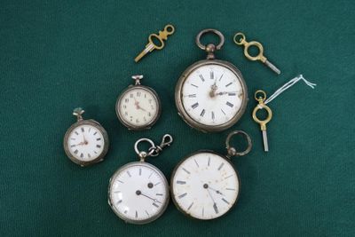 cinq types différents de montres de poche posées sur un fond vert