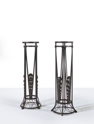 pair of black iron candlesticks with a man ' s head on the top