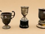 trois tasses en argent posées l'une à côté de l'autre sur une table