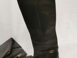 a hand reaching for a pair of boots that are next to a purse