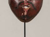 a close up of a wooden mask on a stand on a table