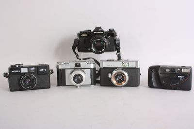 several cameras are lined up on a white surface with a white background