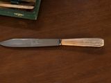 a knife that is sitting on a table next to a box of pencils