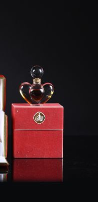 two perfume bottles sitting on top of a red box next to each other