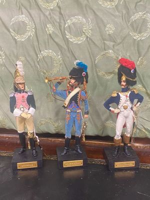 trois figurines de soldats exposées sur une table