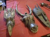 trois masques en bois posés sur une table recouverte d'une nappe rouge