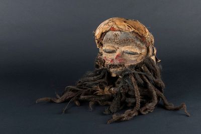 une tête en bois avec des dreadlocks sur fond noir