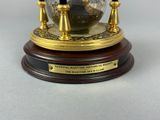 a glass globe with a clock on it on a wooden base
