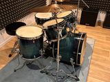 a drum set up in a recording room with a microphone