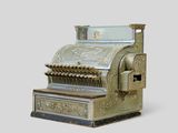 a silver and gold cash register sitting on a white surface