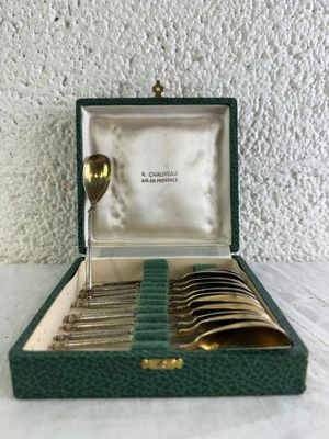 un coffret vert contenant de l'argenterie sur une table