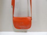an orange purse hanging on a white wall with a white wall in the background