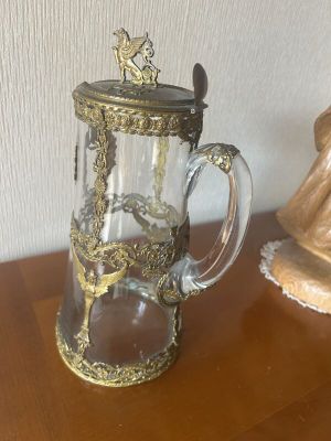 a glass pitcher on a table with a statue in the background