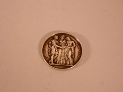 a silver coin with a picture of a group of people on it