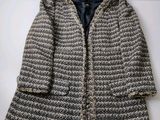 un gros plan d'un manteau tricoté posé sur une surface blanche