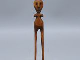 une petite sculpture en bois représentant une personne dont la tête est dotée d'un visage