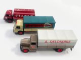 trois camions miniatures posés les uns à côté des autres sur une surface blanche