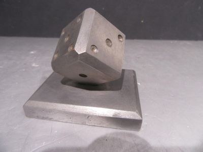 un objet métallique qui ressemble à un dé posé sur un bloc