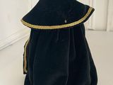 black velvet purse with gold trimming and a ring on top of it