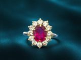 a close up of a ring with a ruby stone surrounded by white diamonds
