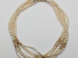 a close up of a necklace with pearls on a white surface