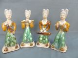 three ceramic figurines of women with musical instruments on a blue background