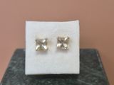 a pair of earrings sitting on top of a marble block