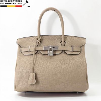 un sac à main en cuir beige muni d'un fermoir métallique sur la poignée