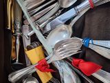 many spoons and forks in a box with a red ribbon