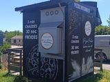 a black outhouse with graffiti on the side of it