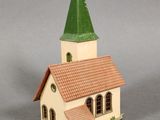 a small toy church with a green steeple on top