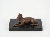 statue of a dog laying down on a black marble base