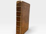 an old book with a brown cover sitting on top of a white surface