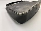 black leather purse on a white surface with a black handle