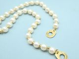 a close up of a pearl necklace on a blue surface