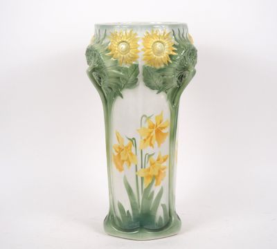 un vase sur lequel sont peintes des fleurs jaunes sur fond blanc