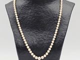 a white pearl necklace on a black mannequin