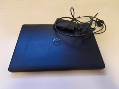 un ordinateur portable Dell avec son cordon d'alimentation et son chargeur, posé sur une table